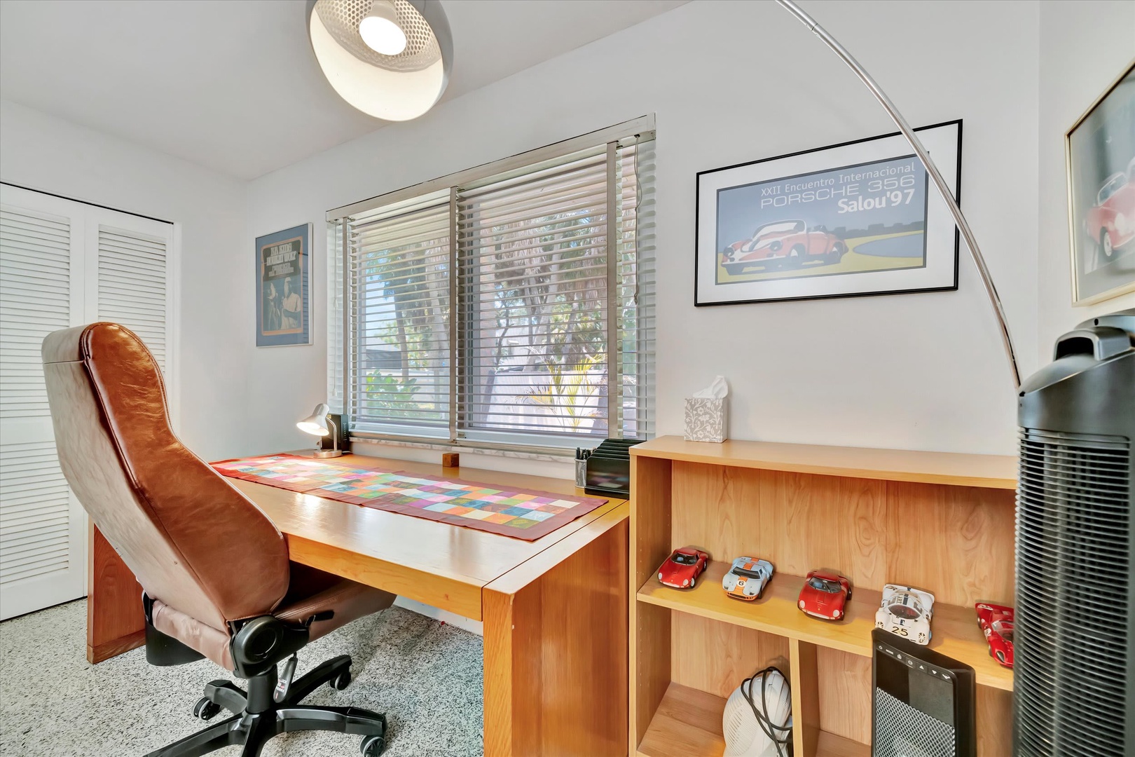 Work comfortably at your modern desk with plenty of natural light filtering through the window blinds. Sleek design meets function in this bright, creative space.