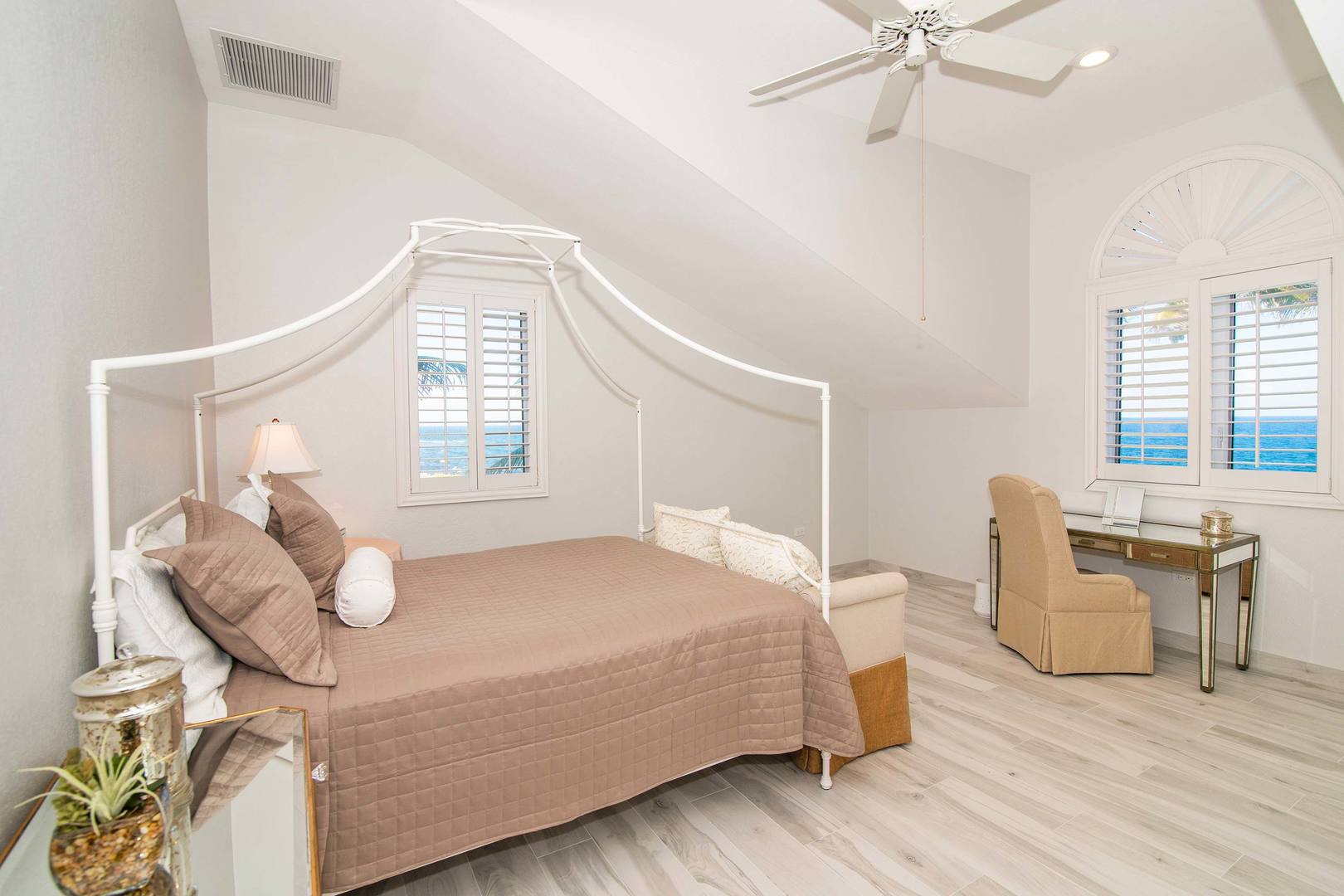 Bedroom #1 with four poster queen bed, desk with chair, and ocean views.