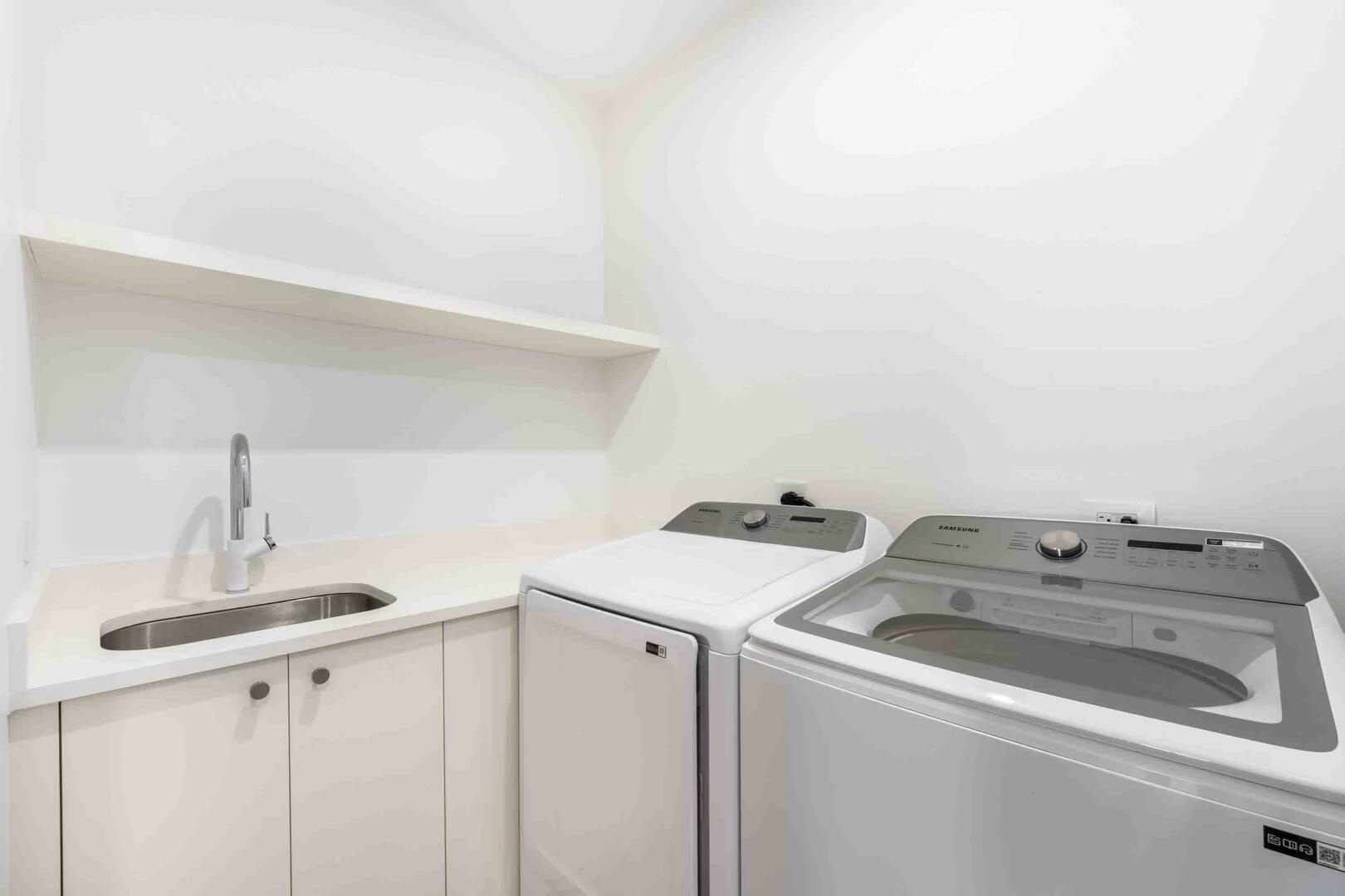 In-unit laundry room with washer, dryer, and utility sink.