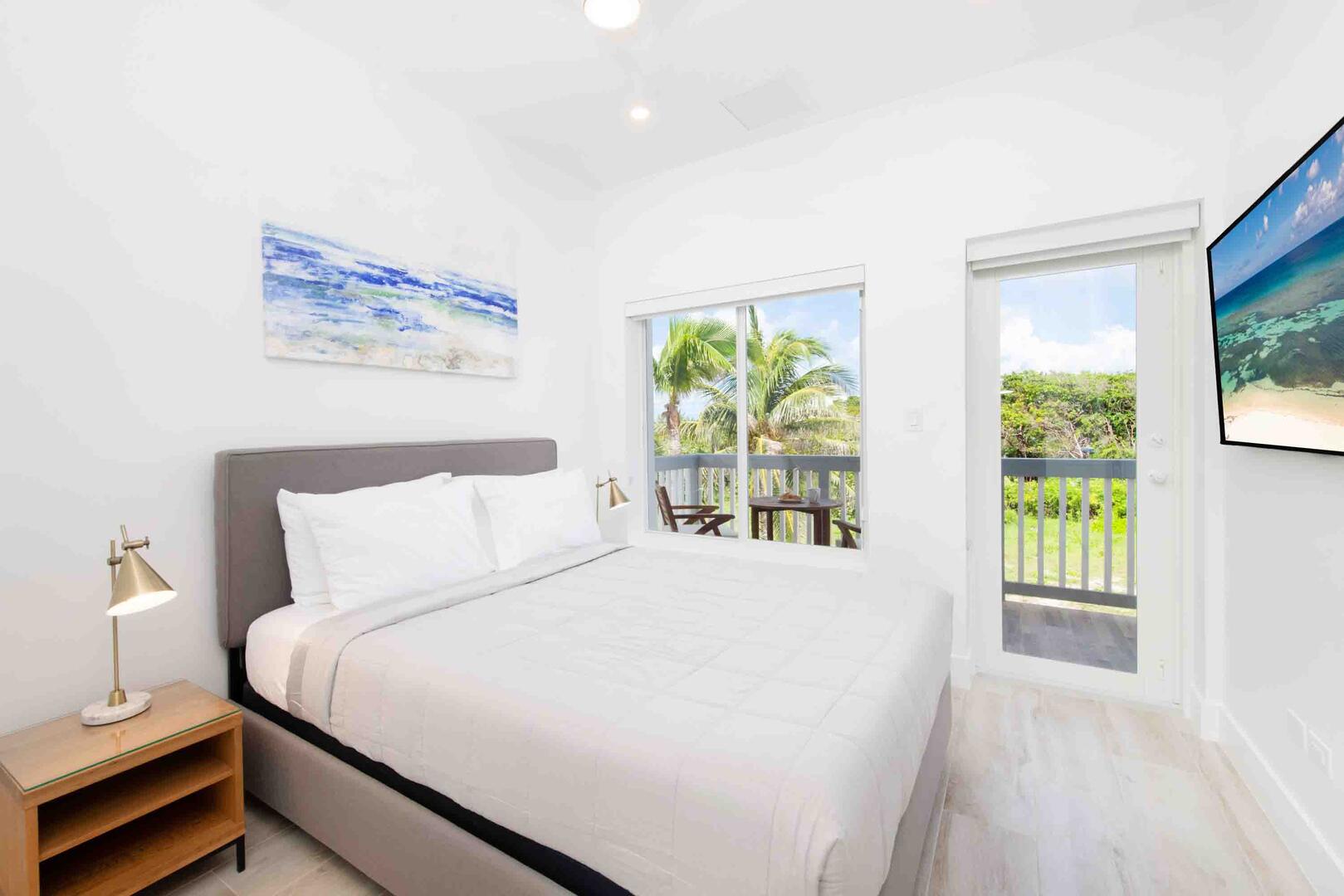 Bedroom 2 with queen bed, television, and walkout access to a shared balcony.