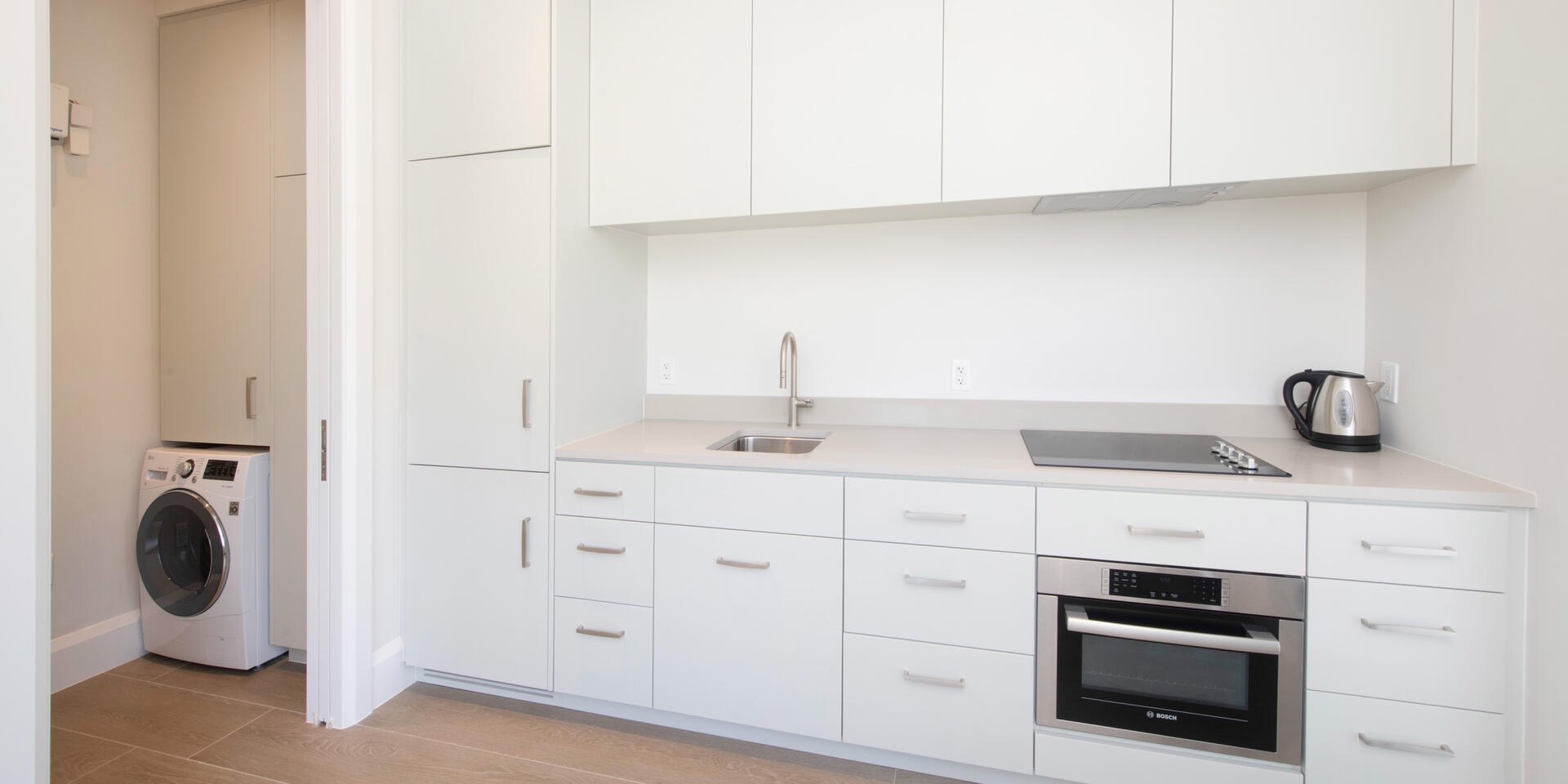 Guesthouse kitchenette with sink, stovetop, microwave, and laundry room.