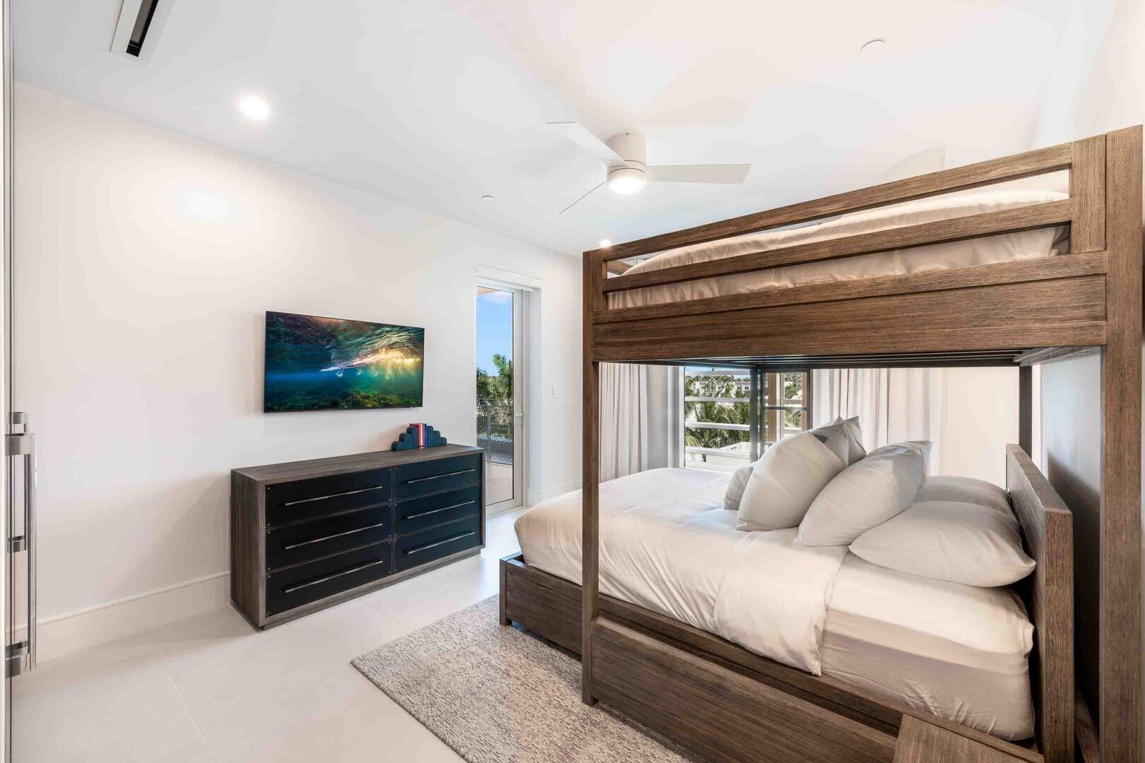 Bedroom 4 is furnished with a single-over-queen bunk bed, and a SmartTV. It also features walkout access to the land-side balcony.