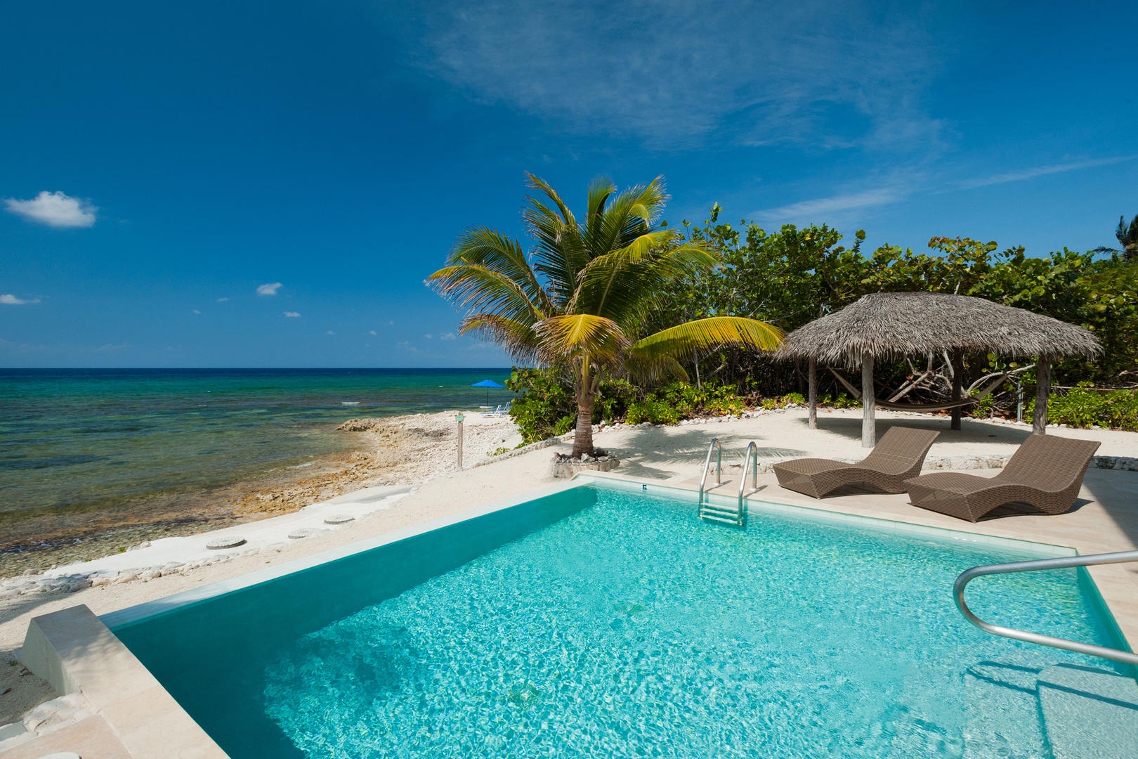 Lounge by your private pool with a stunning view of the Caribbean.