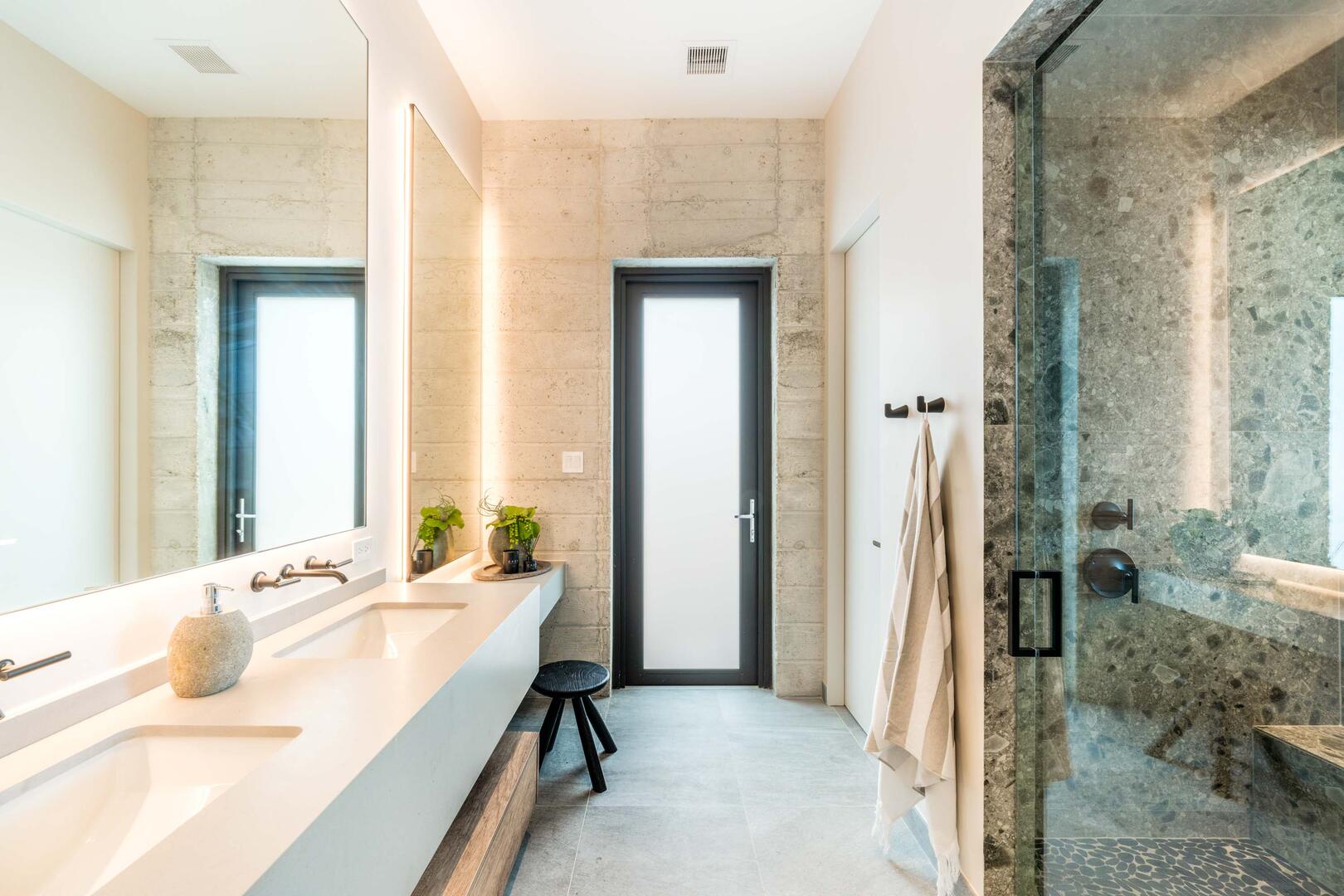 Suite 1 ensuite bathroom with double vanity, multiple mirrors, lighted make-up station, walk-in oceanview shower