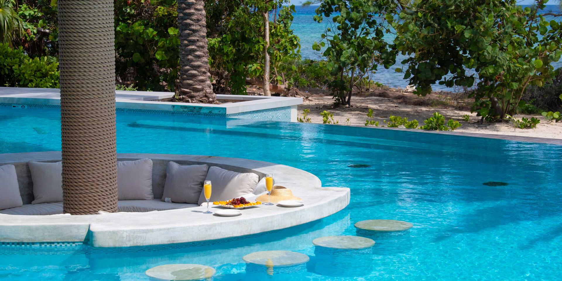 The villa's private pool is customized with a sunken pillow lounge and swim-up bar with submerged stools.