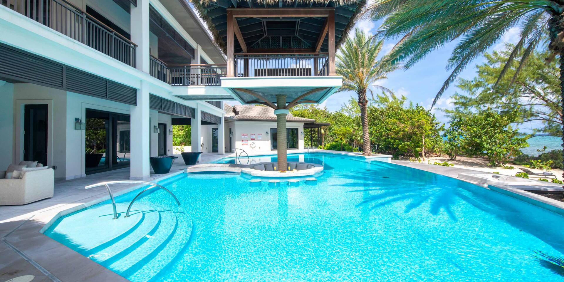View of the villa's enormous pool with sunken pillow lounge and floating birdcage cabana perched above it.