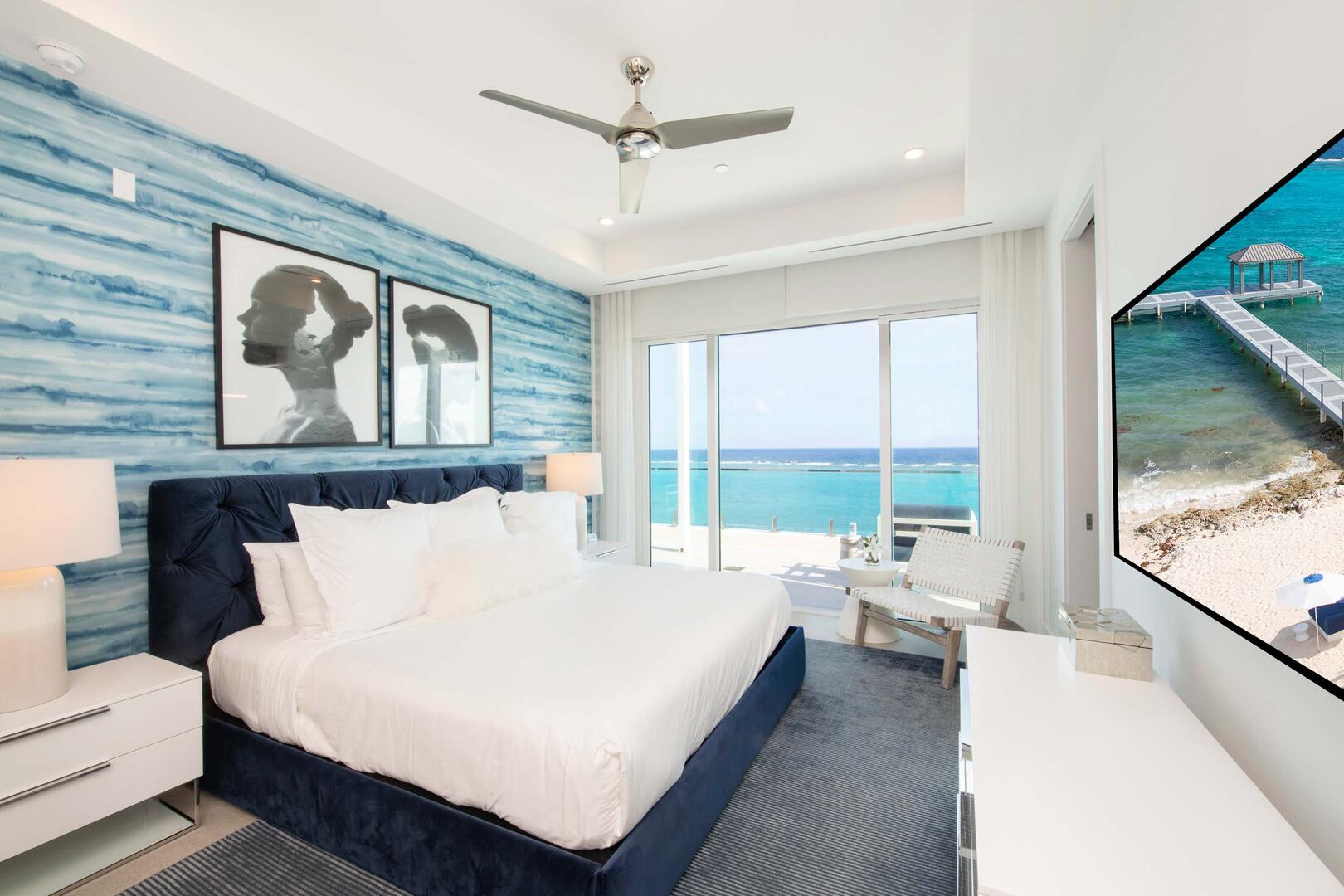 Primary Suite 2: king bed, ocean views, walk-out access to the open-air balcony, SmartTV, closet, ensuite bath with dual vanity, and walk-in shower.