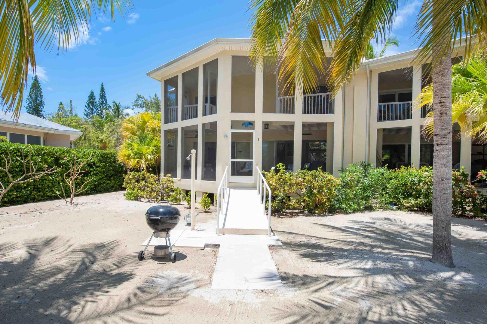 The screened lanai opens to a sandy backyard. A charcoal grill is provided for island cookouts by the water.