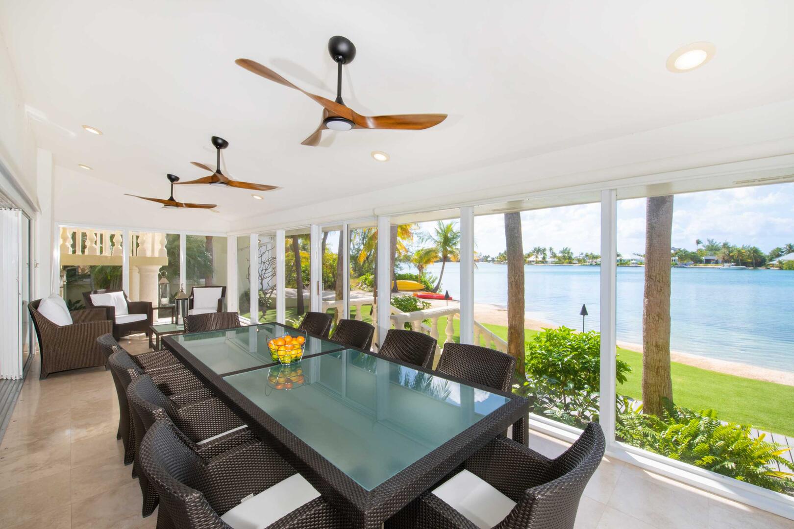 The sun room dining table seats 10 guests with waterfront views.