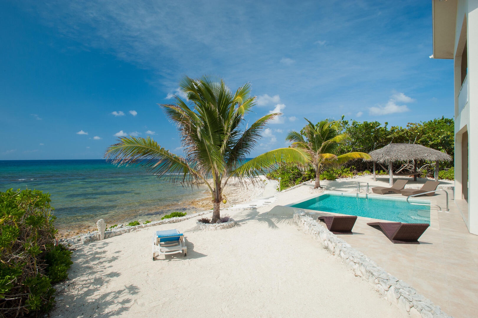 Backyard scene with private pool and hammock cabana at the ocean's edge.