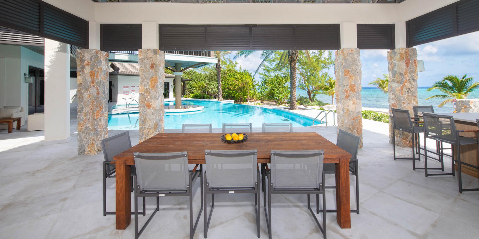 The pool is flanked by a large dining pavilion furnished with a summer kitchen and alfresco dining table.