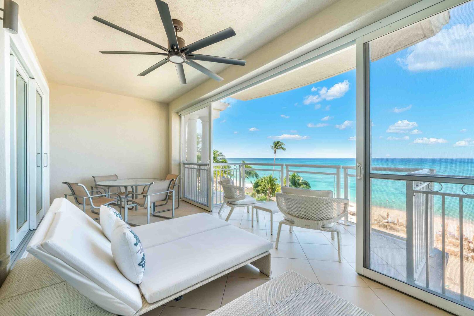 Spacious furnished balcony with sunbeds, alfresco dining table, and lounge seating.