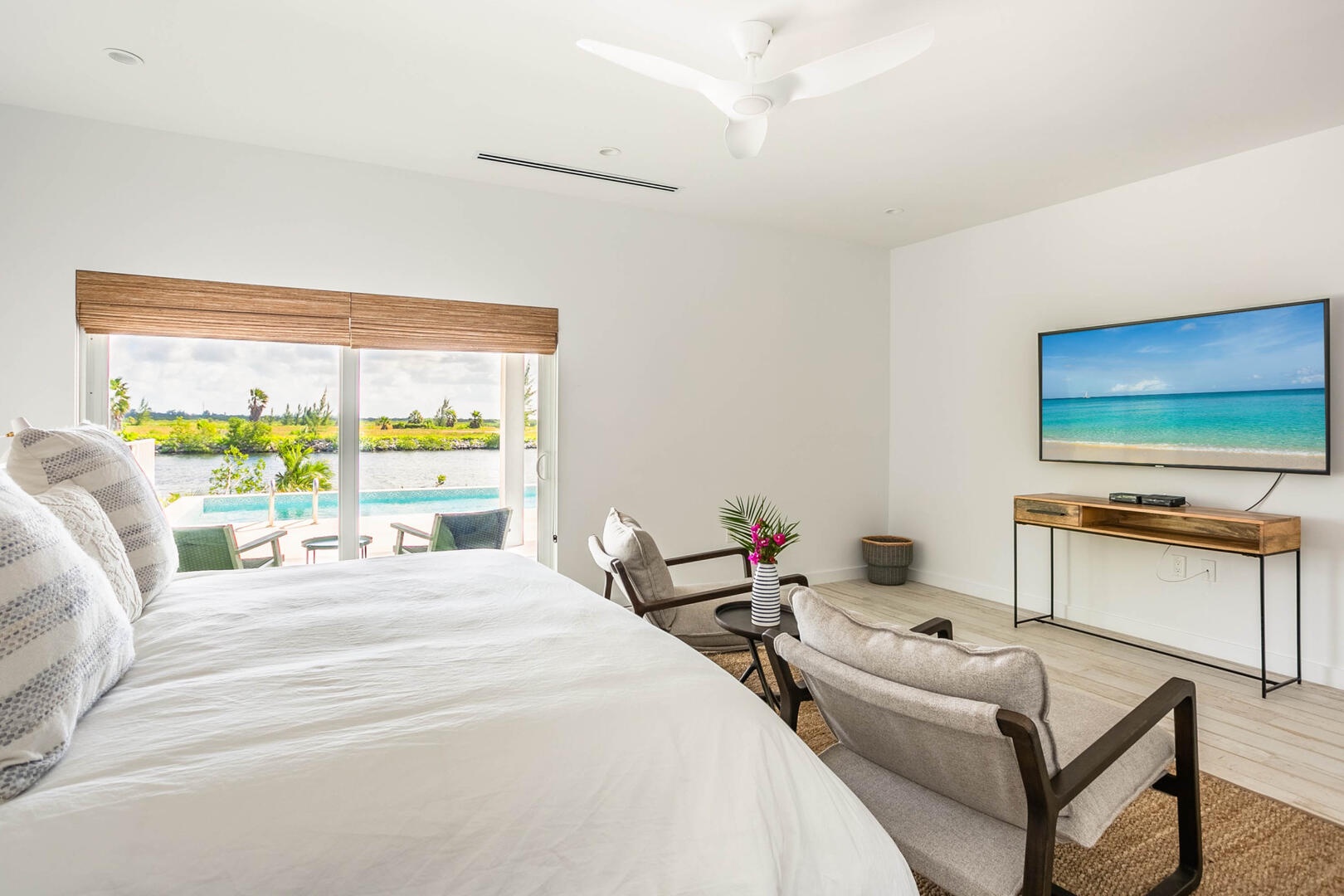 Primary suite with king bed, television, and walk-out access to the pool deck.