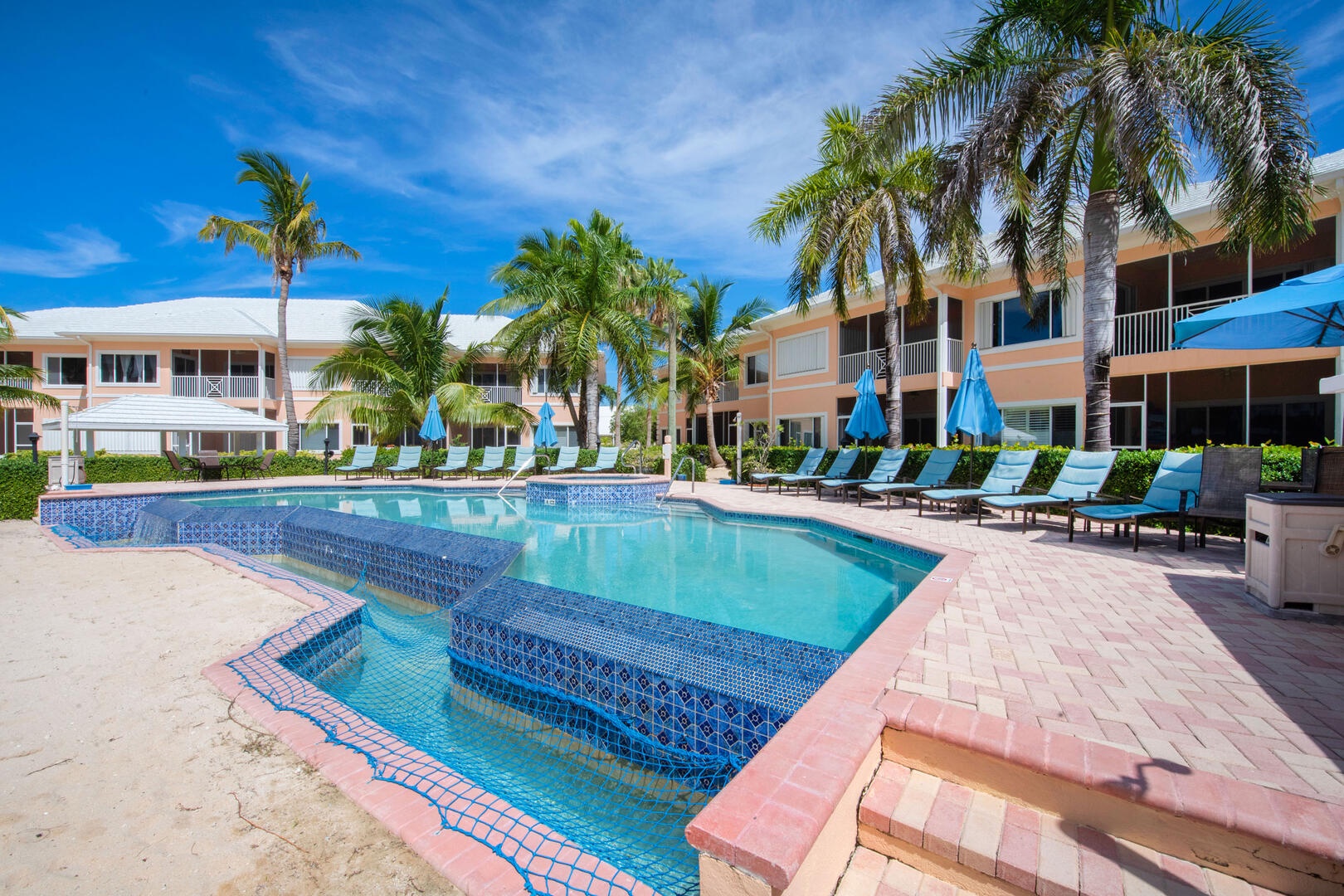 Communal pool and spa with plenty of sun beds and shade umbrellas.