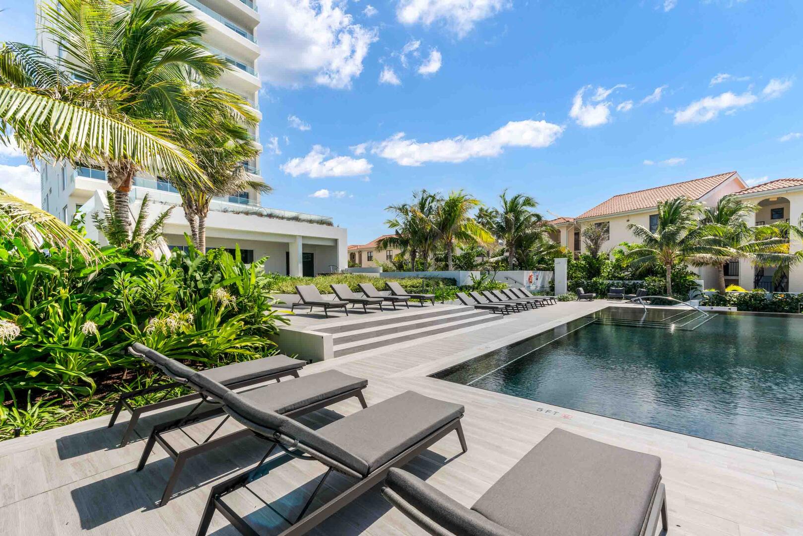 The communal pool deck is furnished with sun beds.