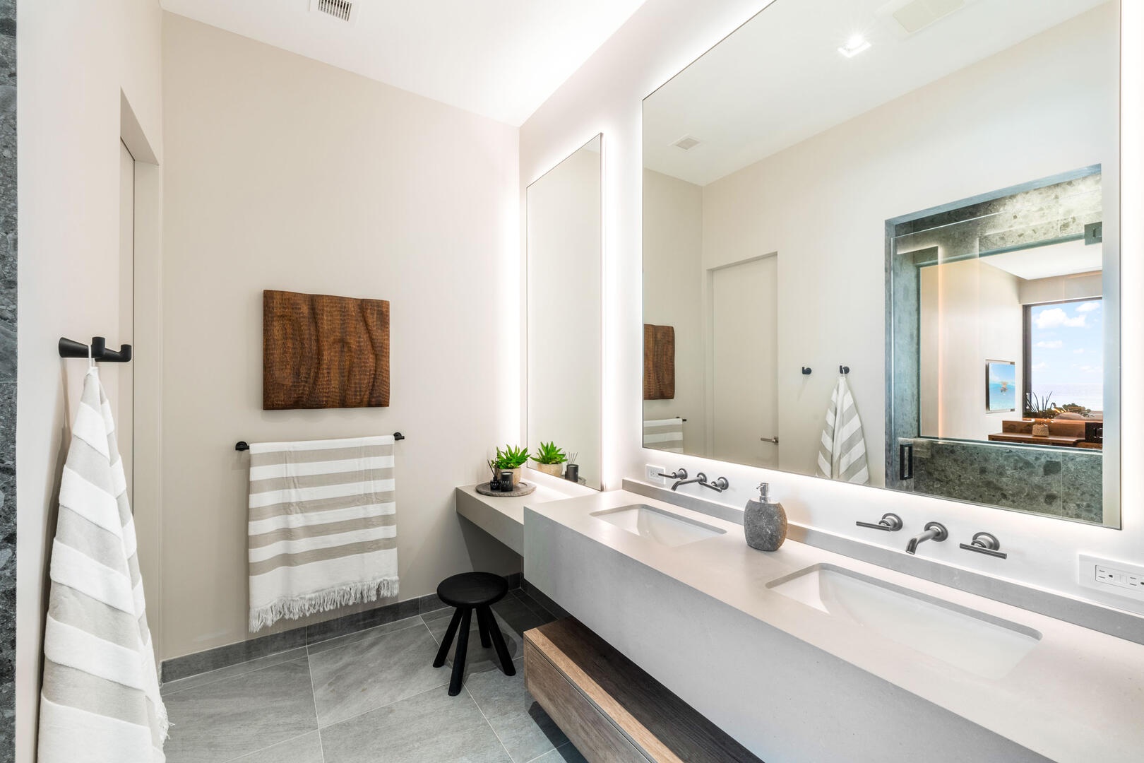 Suite 1 ensuite bathroom with double vanity, multiple mirrors, lighted make-up station, walk-in oceanview shower