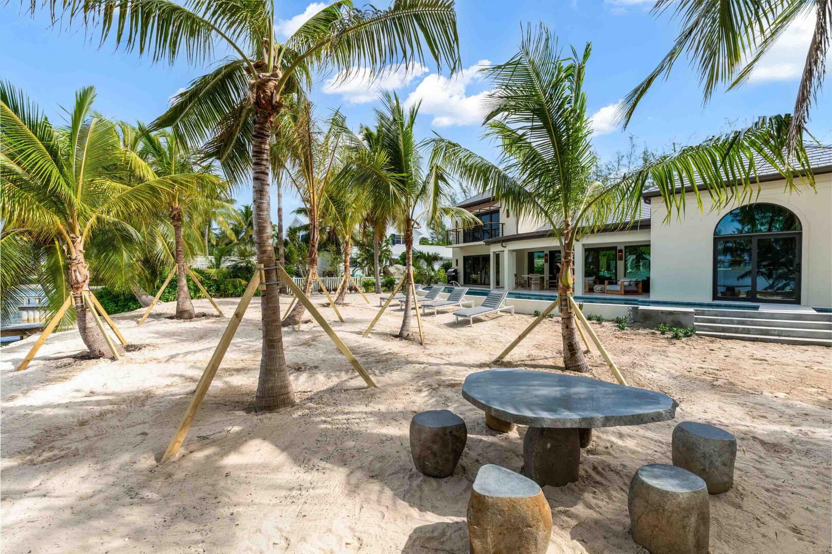 Sandy backyard beachfront with stone picnic table by the water's edge.
