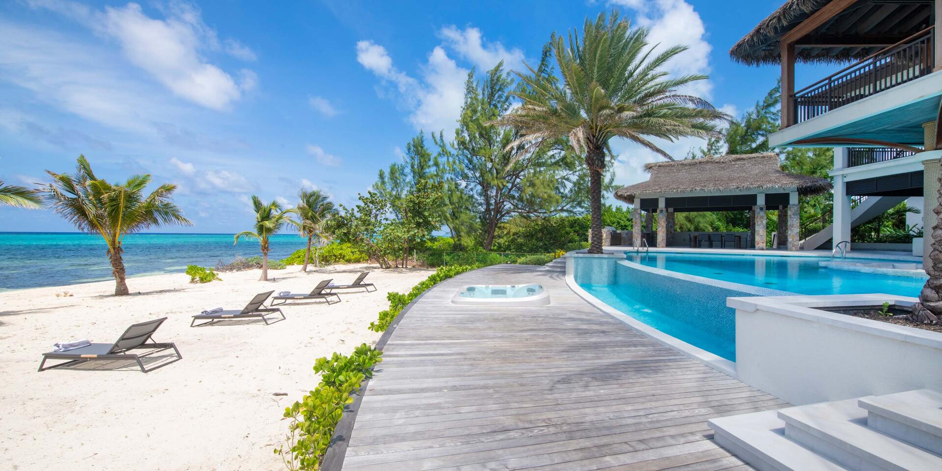 Backyard beach with sun beds and a sunken jacuzzi in the pool deck.
