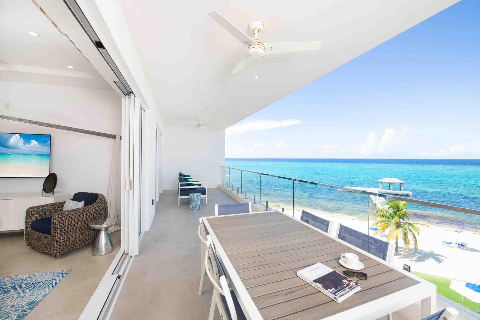 Private oceanfront balcony furnished with an al fresco dining table and sofa seating.