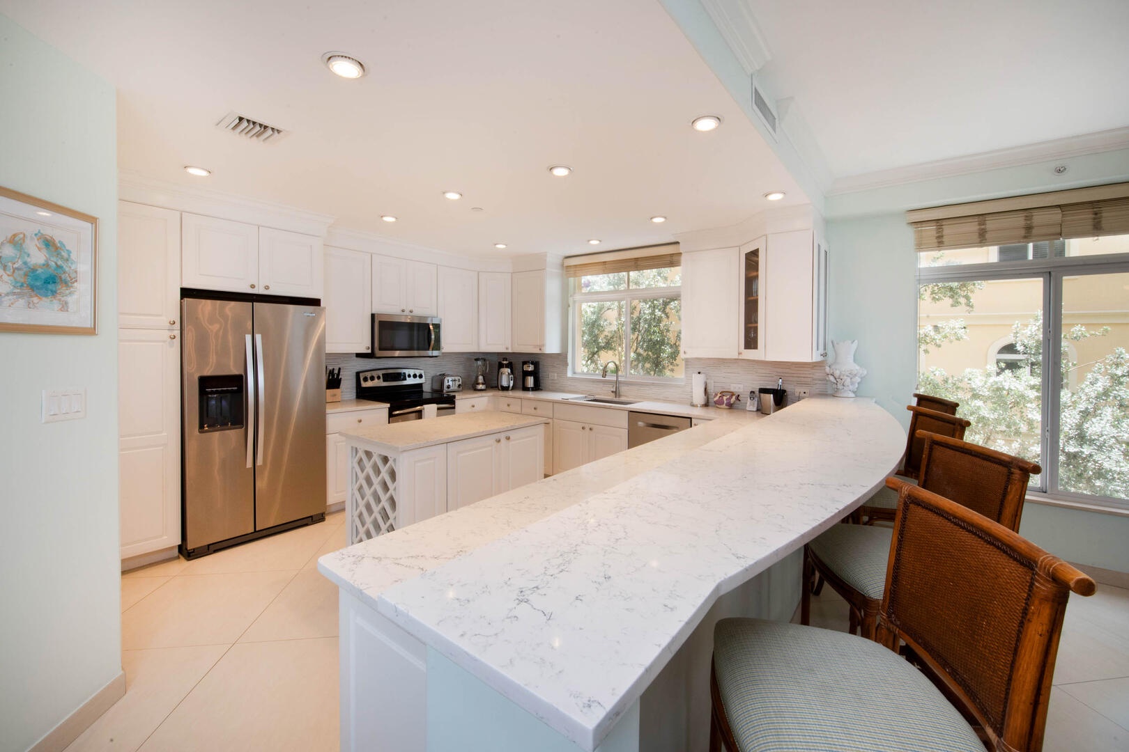 Full kitchen with modern appliances and breakfast bar seating.