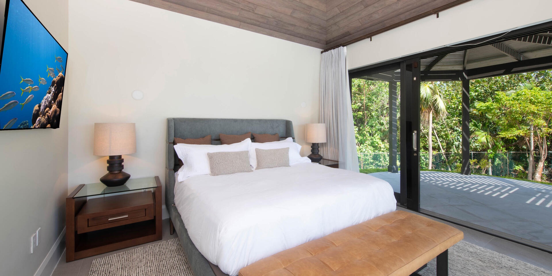 Bedroom 3 is in the main villa's detached pool house and is furnished with a king bed, SmartTV, and walkout access to a private cabana.