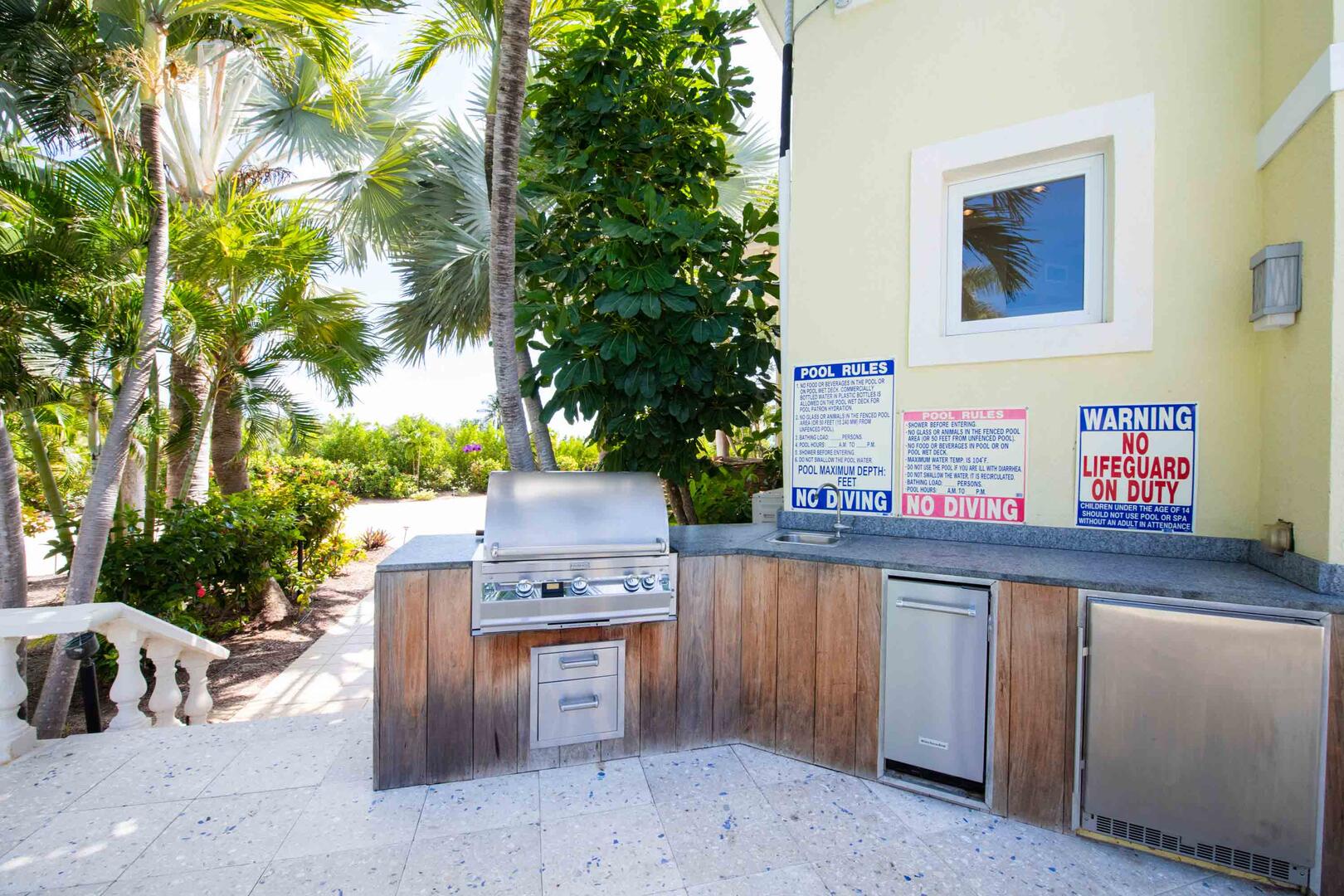 Outdoor kitchen with propane grill, sink, plus under-the-counter fridge, and ice maker.