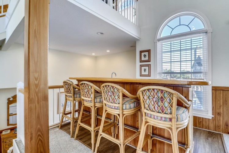 Picture yourself starting your day at this charming bar area, sipping coffee beneath soaring ceilings and natural light streaming through the arched window. The warm wood and patterned bar stools create an inviting spot to gather and relax.