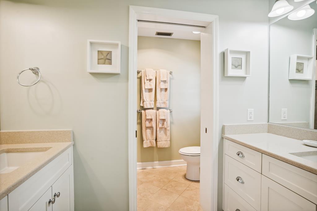 Your private bathroom features a clean, calming design with fresh towels, dual vanities, and coastal artwork—ideal for unwinding after a day exploring.