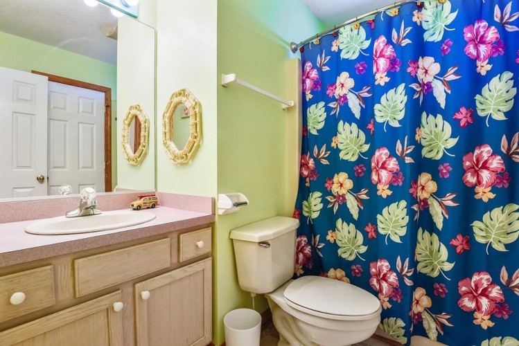Refresh in your private bathroom, featuring a vibrant tropical shower curtain, clean vanity, and thoughtfully arranged amenities to make you feel at home.