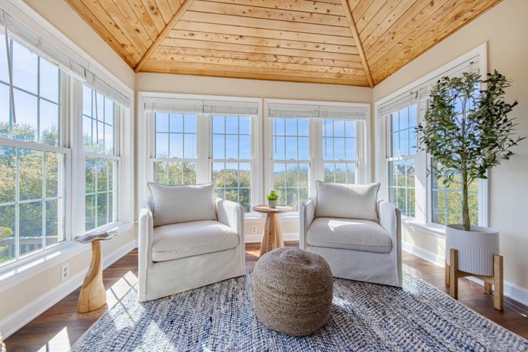 Settle into your private sunroom where natural light pours through floor-to-ceiling windows, offering panoramic views of the lush surrounding landscape. This cozy nook is perfect for morning coffee or quiet reflection.