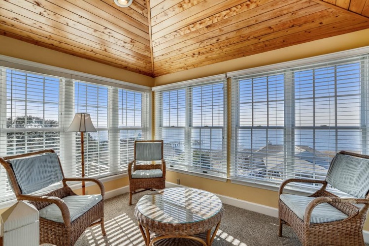 Settle into this sunlit corner with your morning coffee and watch the waves dance across the water through floor-to-ceiling windows that frame endless waterfront views.