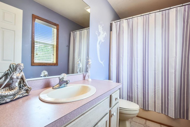 Step into your private bathroom, where soft purple walls and a whimsical mermaid accent create a calming, coastal vibe perfect for unwinding after a day of exploring.