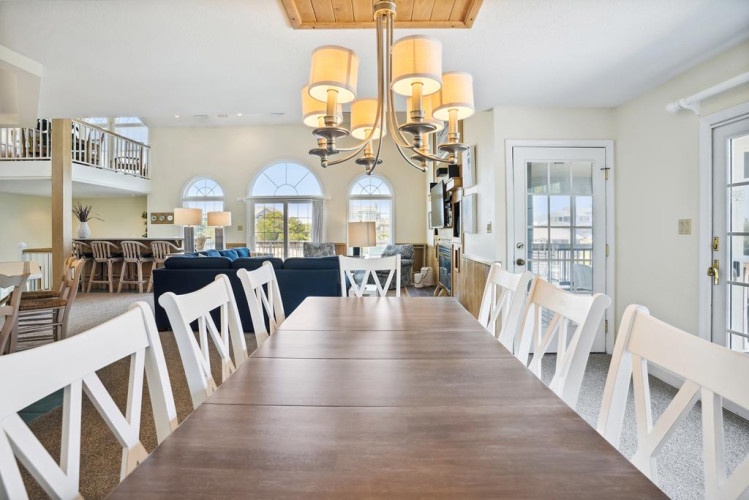 Gather your loved ones around this beautiful dining table, where sunlight streams through arched windows and vaulted ceilings create an airy, welcoming atmosphere for memorable meals together.