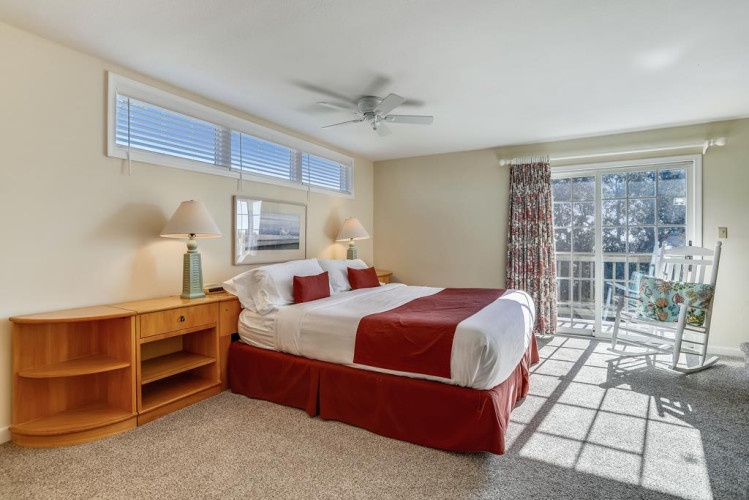 Step into your bright, inviting bedroom where natural light pours through large windows. Relax on the comfortable bed, enjoy gentle breezes from the ceiling fan, and savor peaceful views from your private balcony.