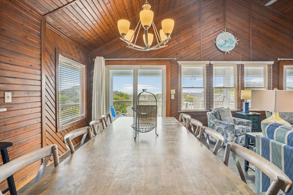 Gather around this spacious dining table under warm wood-paneled ceilings and enjoy meals with your group while natural light pours in through expansive windows framing serene outdoor views.