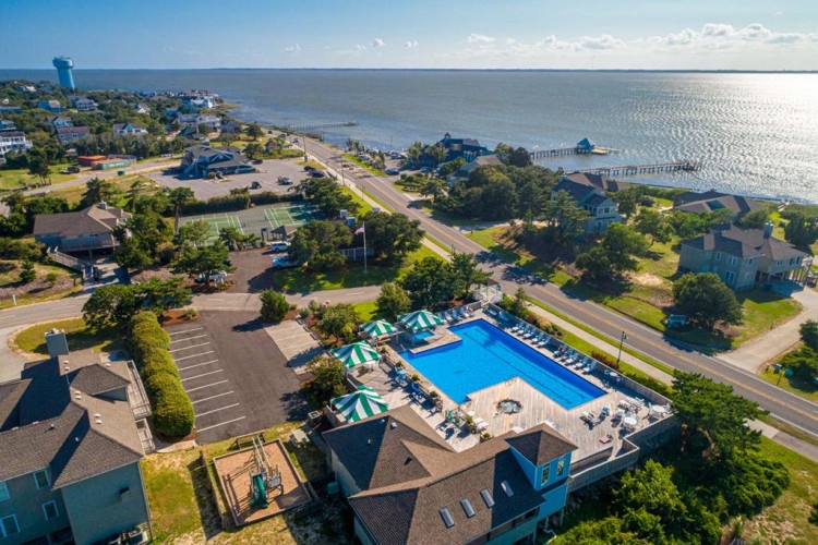 Coastal retreat nestled on the waterfront with sparkling pool and expansive bay views, surrounded by serene seaside neighborhood and lush greenery.