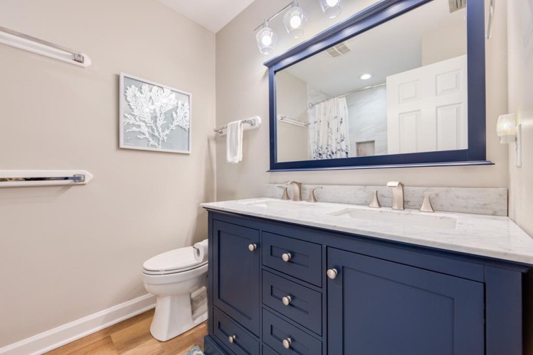 Freshen up in your private bathroom with its elegant navy vanity, marble countertop, and soft lighting—everything you need for a comfortable stay.
