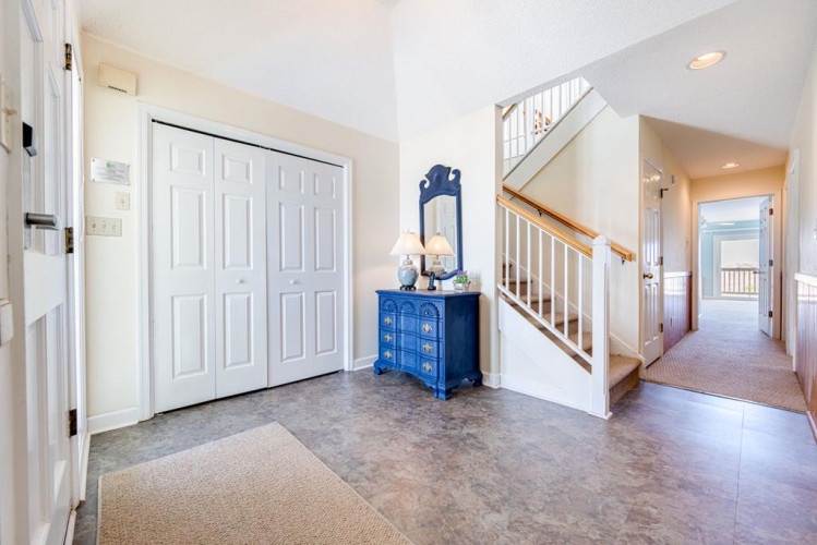 Step into your welcoming foyer, where coastal charm meets home. Natural light fills the space, inviting you up the warm wood staircase to discover your perfect vacation retreat.