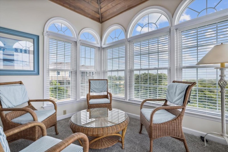 Settle into your private sunlit retreat, where arched windows frame peaceful landscape views and invite natural light to dance across cozy wicker seating—your perfect spot to unwind with morning coffee or a good book.