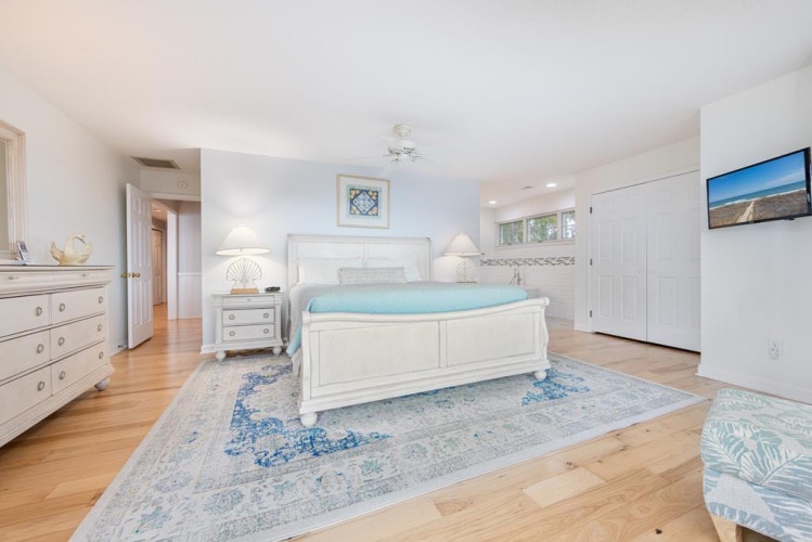 Step into your serene coastal retreat with warm hardwood floors and elegant white furnishings. Sink into the plush bed, unwind in the soft lighting, and enjoy your private space designed for ultimate relaxation.