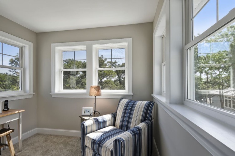 Sink into this cozy reading nook bathed in natural light, with serene tree views through the windows—your perfect retreat for quiet moments.