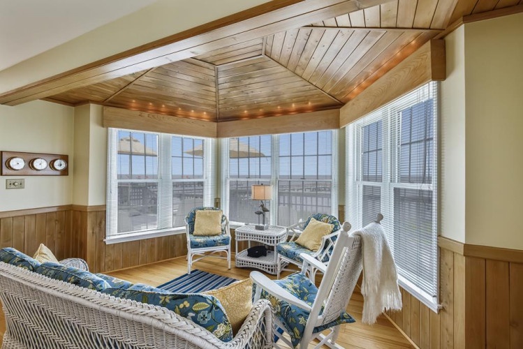 Settle into cozy wicker seating beneath warm wood beams, where natural light floods in and cityscape views unfold. Perfect for morning coffee or quiet moments with a book.