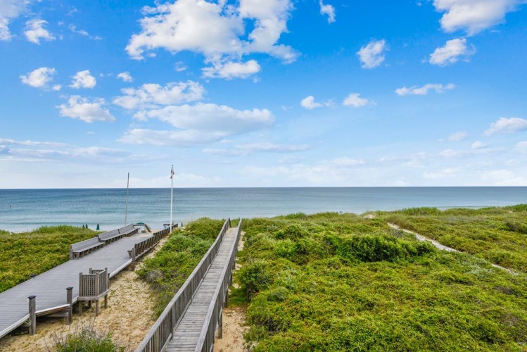 Wooden walkways lead through natural coastal dunes to the beachfront, offering easy access to the shoreline and scenic ocean views for guests.