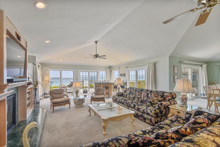 Step into a bright, airy living space where floor-to-ceiling windows frame stunning water views. Relax on comfortable seating as ceiling fans cool you and natural light fills every corner of your home away from home.
