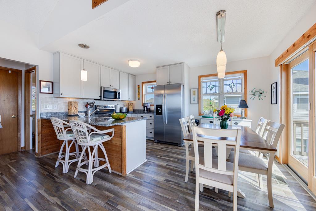 Your open-concept kitchen and dining area blends modern style with warm wood accents, perfect for morning coffee at the breakfast bar or enjoying home-cooked meals together at the inviting dining table.