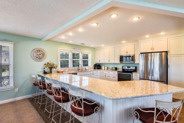 Your spacious kitchen features a large granite island with seating for gatherings, stainless steel appliances, and soft lighting that creates a warm, welcoming atmosphere for preparing and sharing meals together.