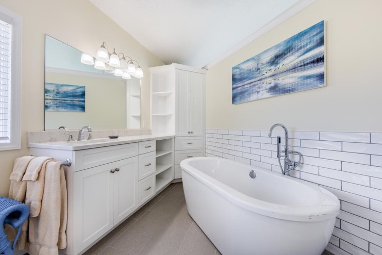 Indulge in your private spa retreat. Soak in the elegant freestanding tub, surrounded by coastal artwork and fresh white tilework that makes every moment feel luxurious.