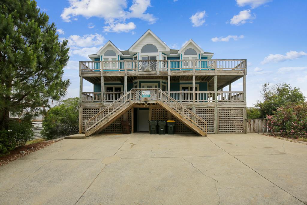 A stunning elevated beach house with expansive balconies and coastal charm, nestled among greenery with ample parking for your arrival.