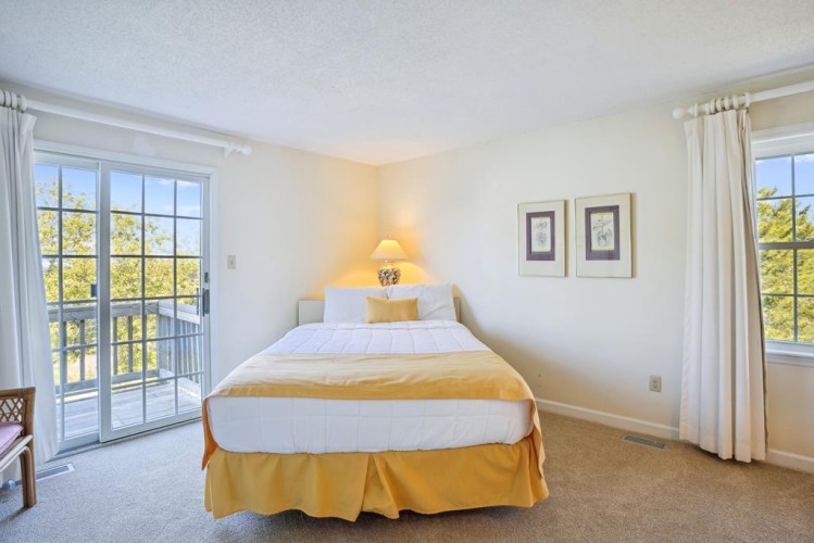 Drift off in your serene bedroom where natural light floods through French doors, offering tree-lined views from your private balcony—your peaceful retreat awaits.