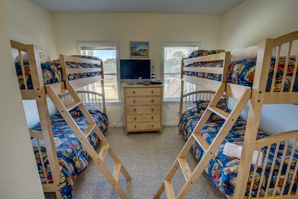 Two sturdy bunk beds offer comfortable sleeping arrangements for the whole family, with bright windows letting in natural light and a TV for entertainment before bedtime.